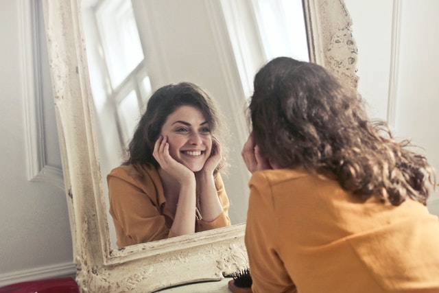 Girl smiling at her reflection in the mirror.