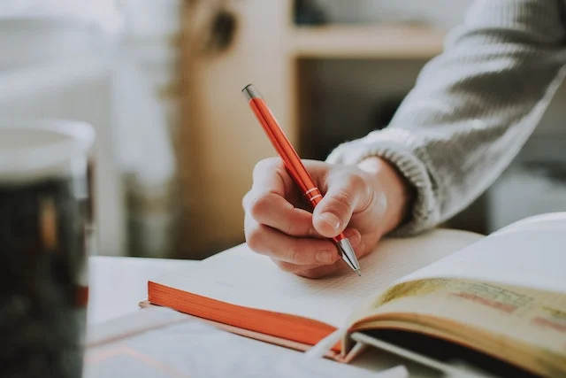 Hand holding a pen on a notebook.