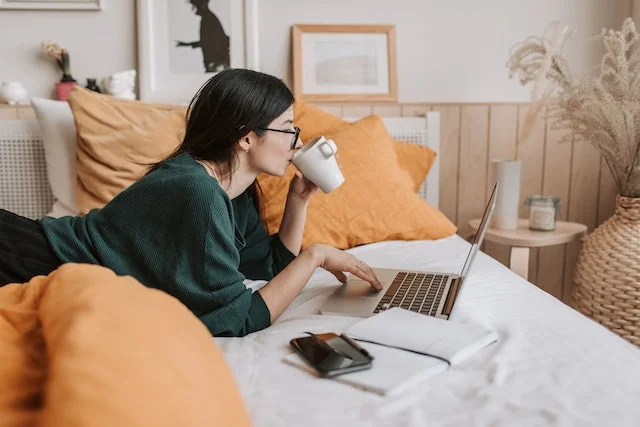 Online business owner working on the bed with laptop.